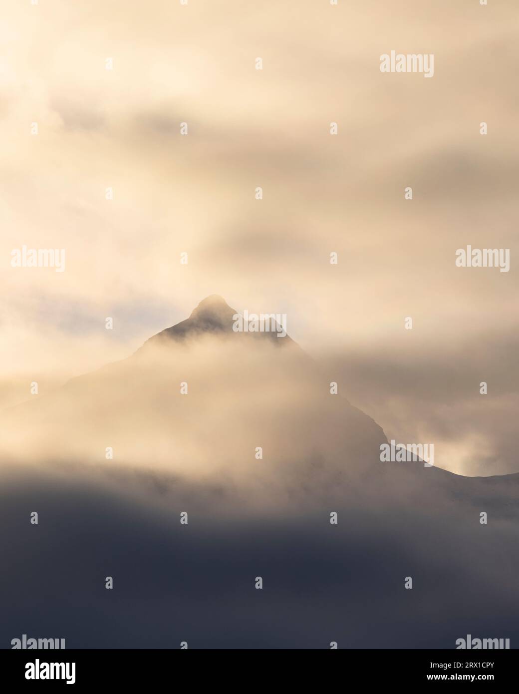 A Mountain Peak Shrouded in Clouds and Sun Stock Photo - Alamy