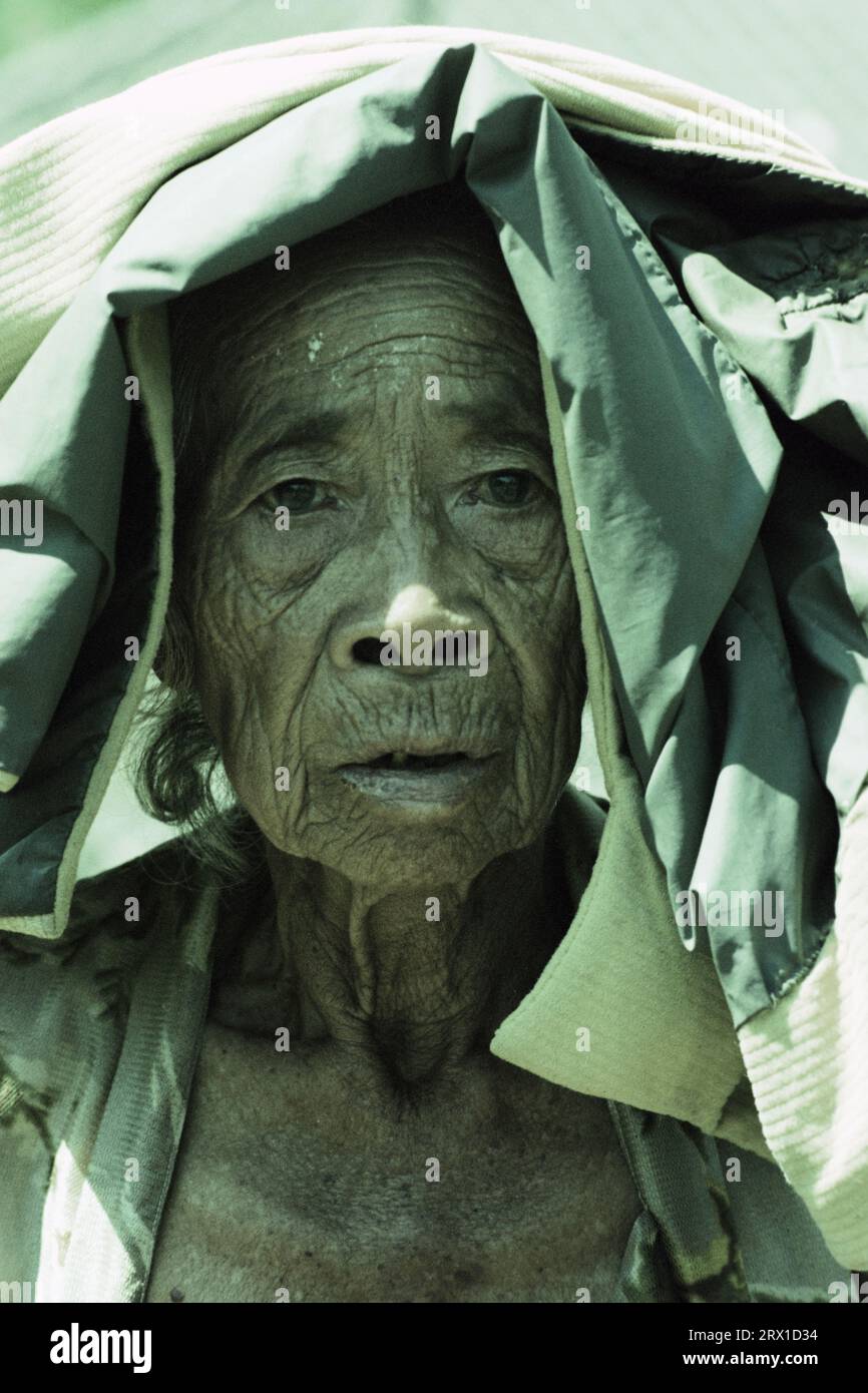 Portrait of an elderly Balinese woman covering her head from the sun Stock Photo