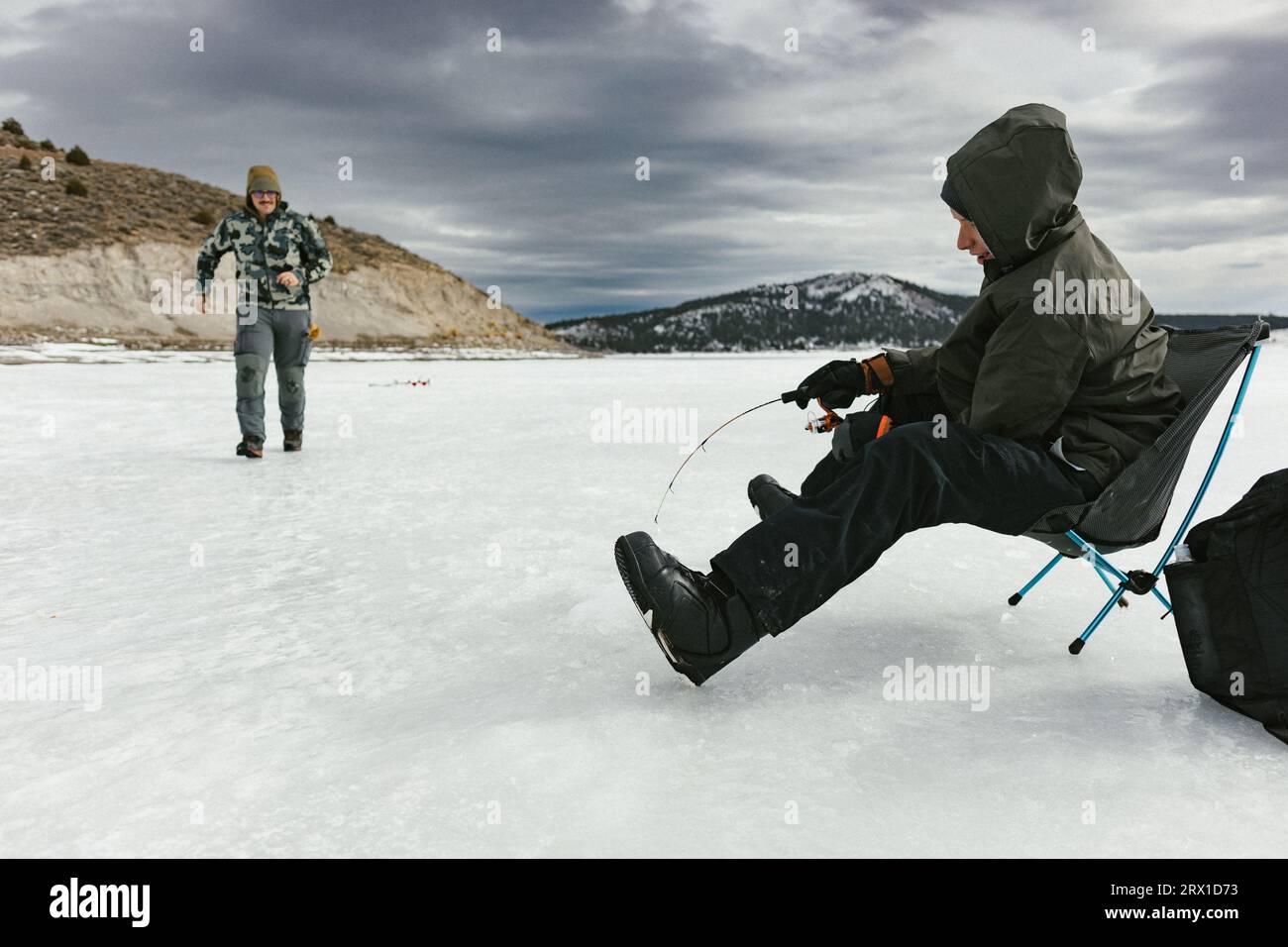 Uncle and boy catch a fish from a frozen lake in winter Stock Photo