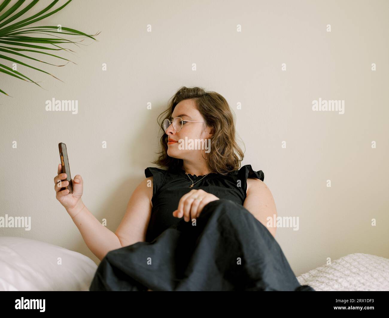 Sitting brunette woman takes a break to check her phone. Stock Photo