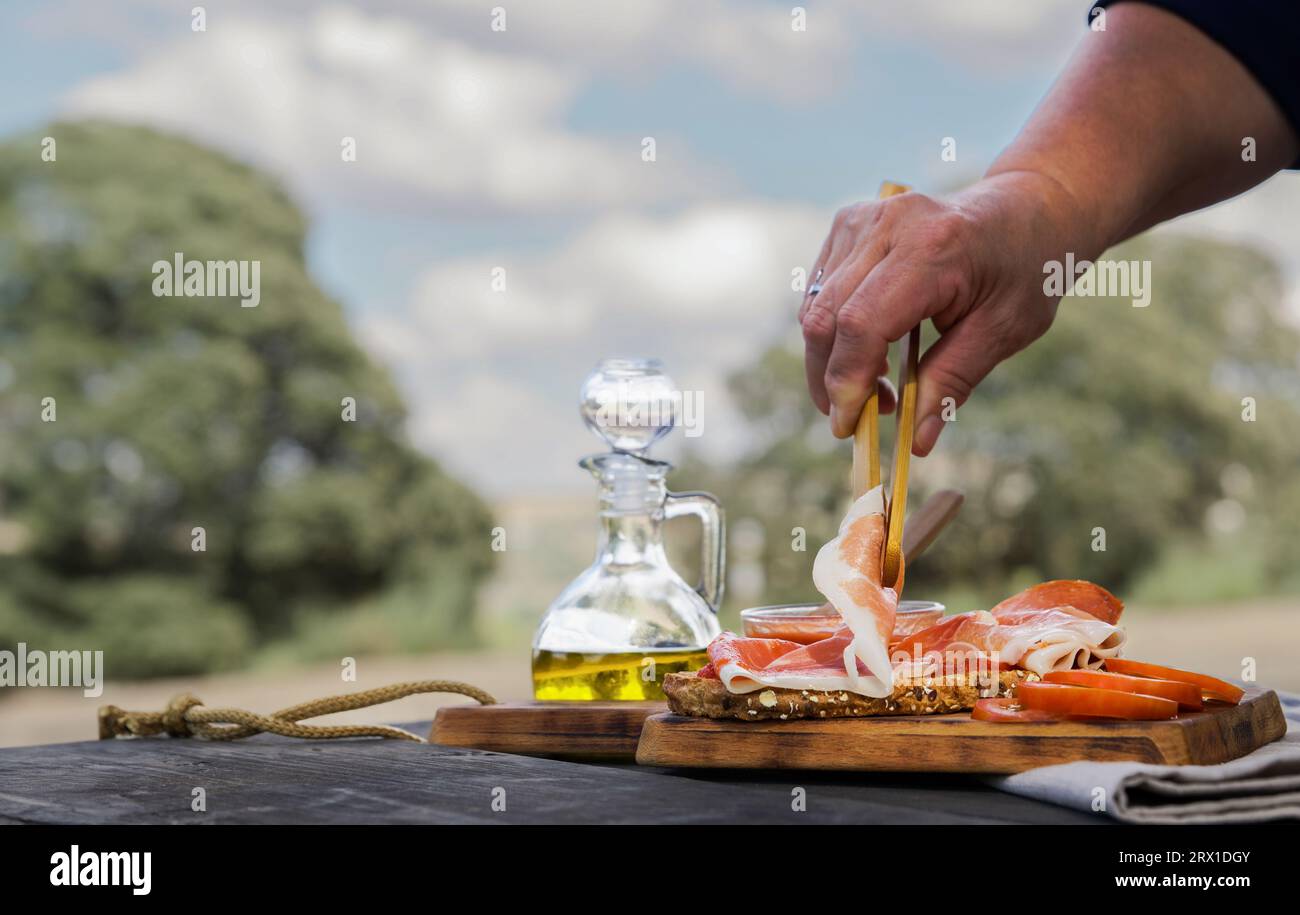 woman putting slices of acorn-fed iberian ham on a slice of bread Stock Photo
