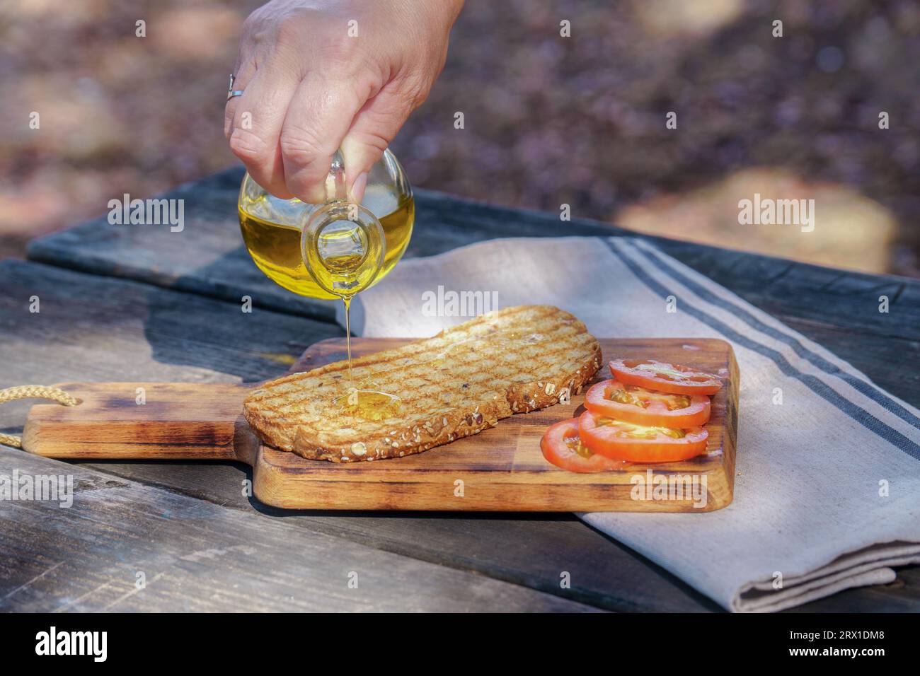 woman pours virgin olive oil on a toast of bread Stock Photo