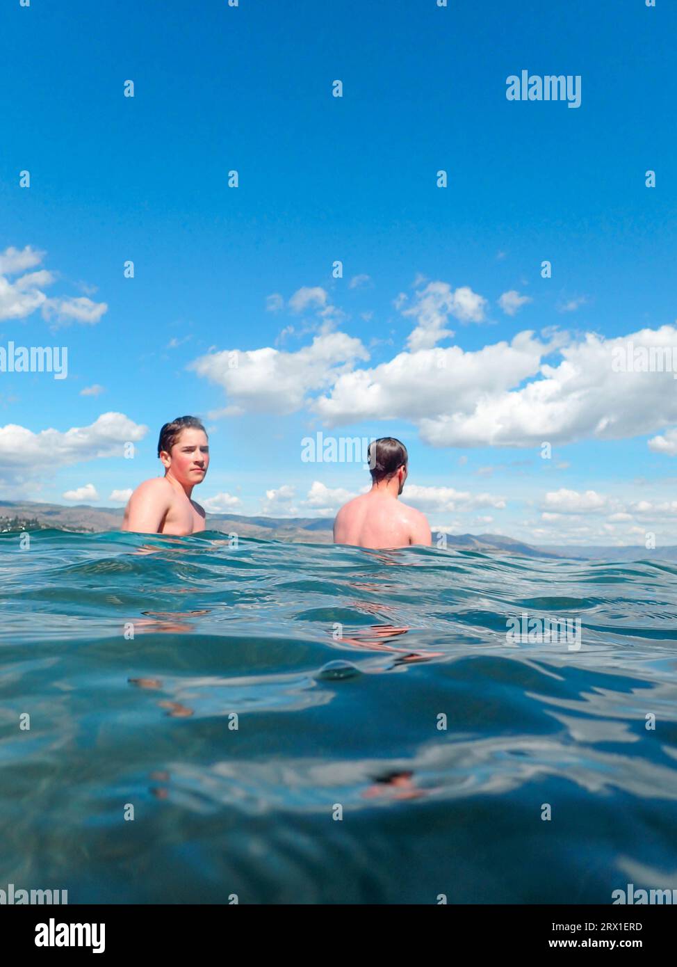 Two Boys In Lake With Crystal Clear Water and Blue Sky Stock Photo