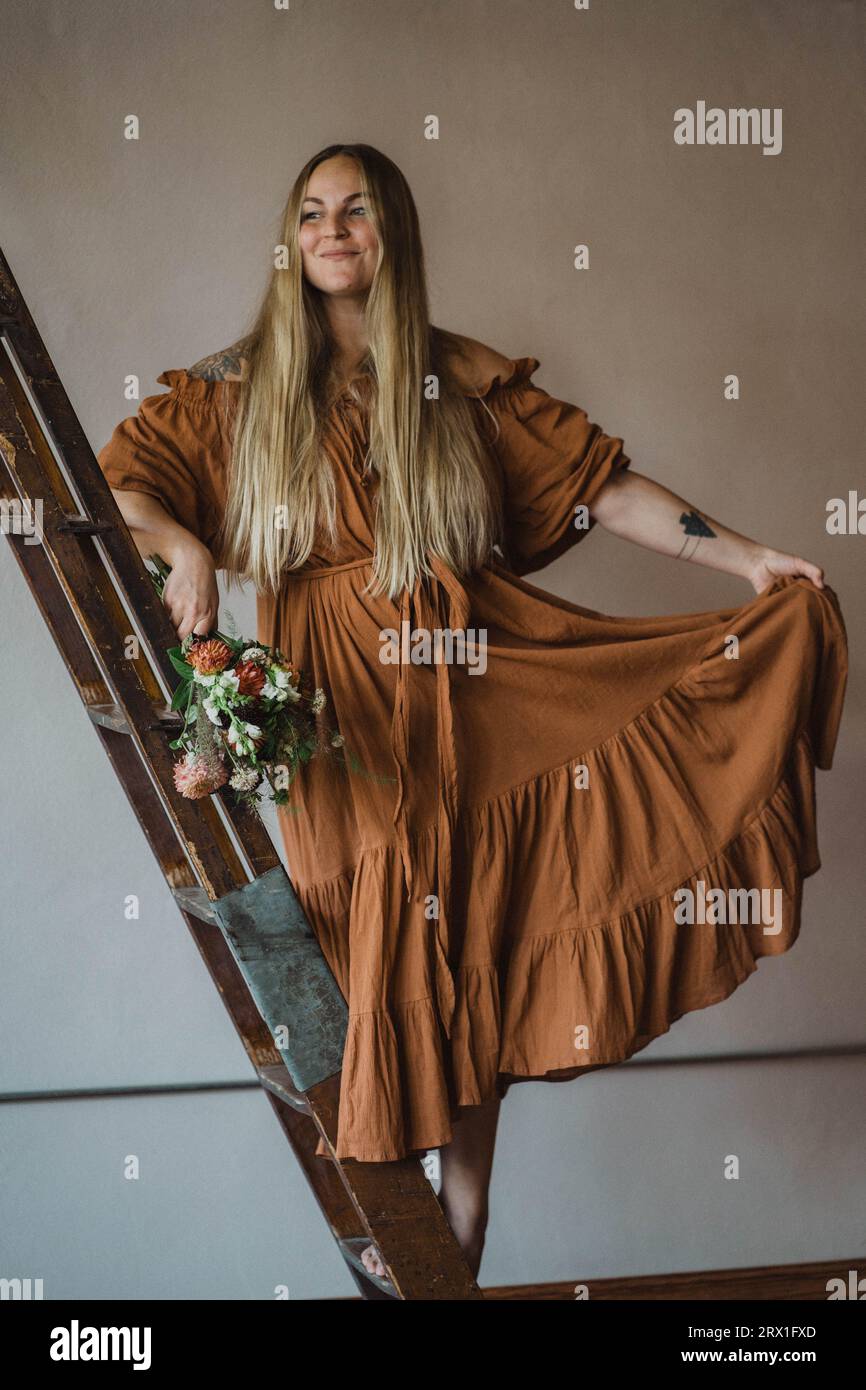 Woman in long dress on library ladder Stock Photo