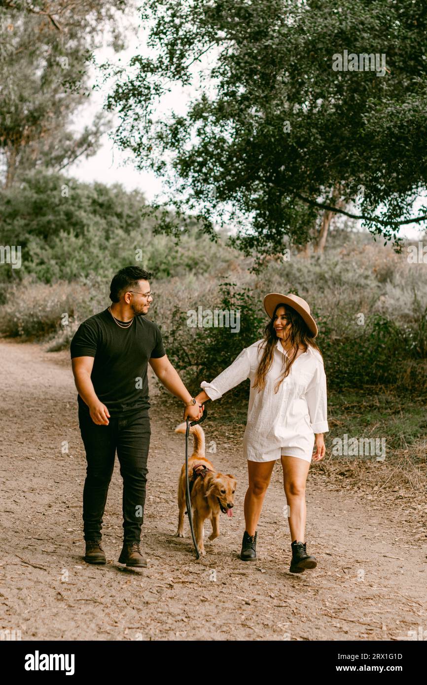 Young couple walking dog in forest Stock Photo