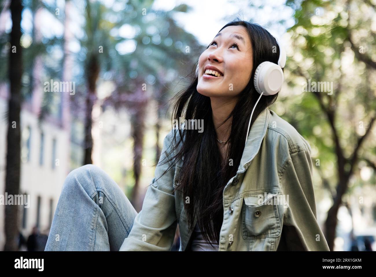 Young hopeful girl sitting on the street looking up. Stock Photo