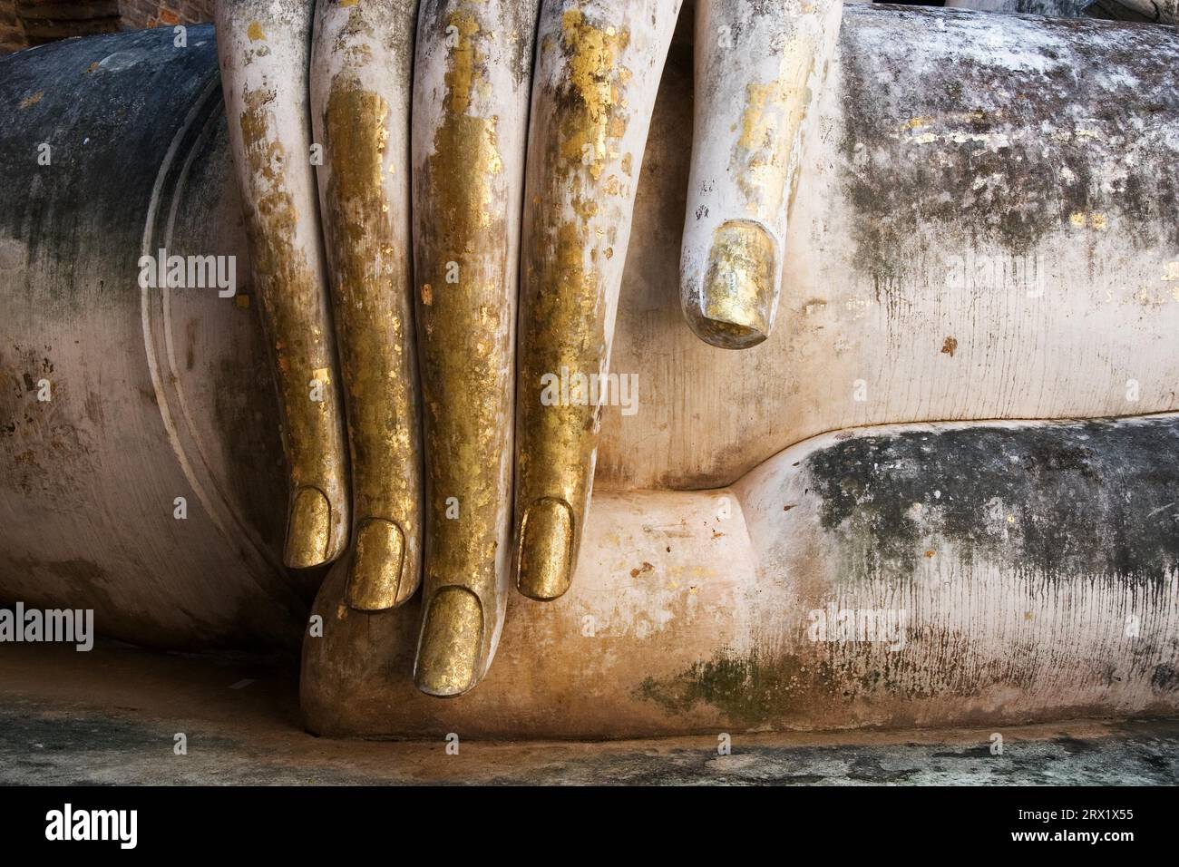 Gold leaf covered fingers of big Buddha statue in Sukhothai, Thailand Stock Photo
