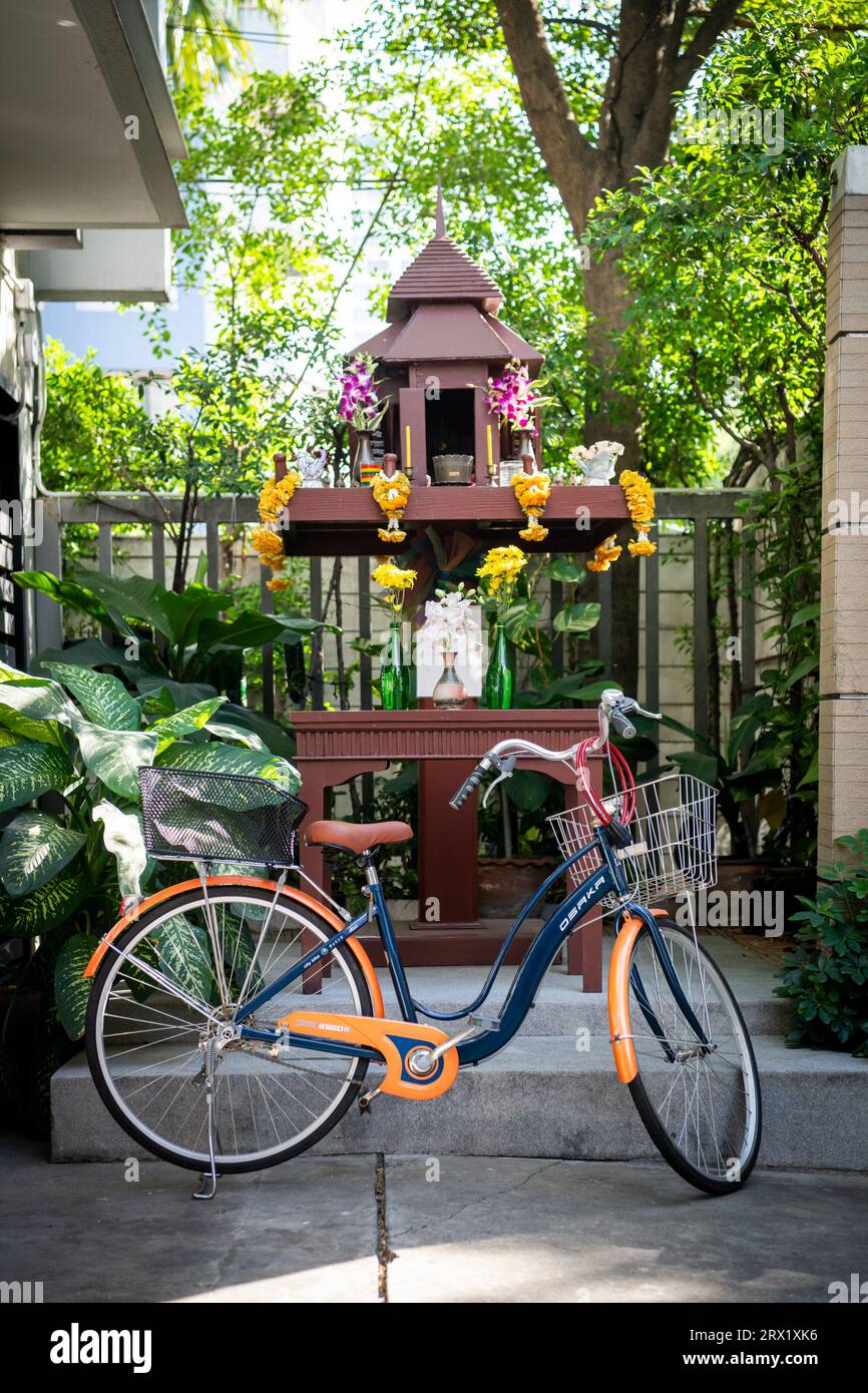 A bicycle stands in front of a Thai spirit house on Soi 8, Sukhumvit Rd. Bangkok, Thailand. Stock Photo