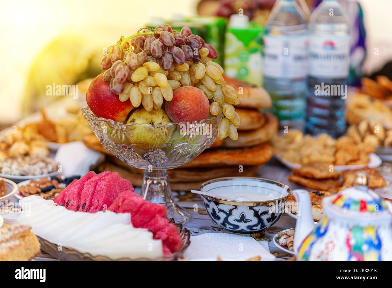 traditional Uzbek dessert - a bunch of green grapes (ladies fingers), slices of watermelon with bread. Bowl national pattern - Cotton material ikat on Stock Photo