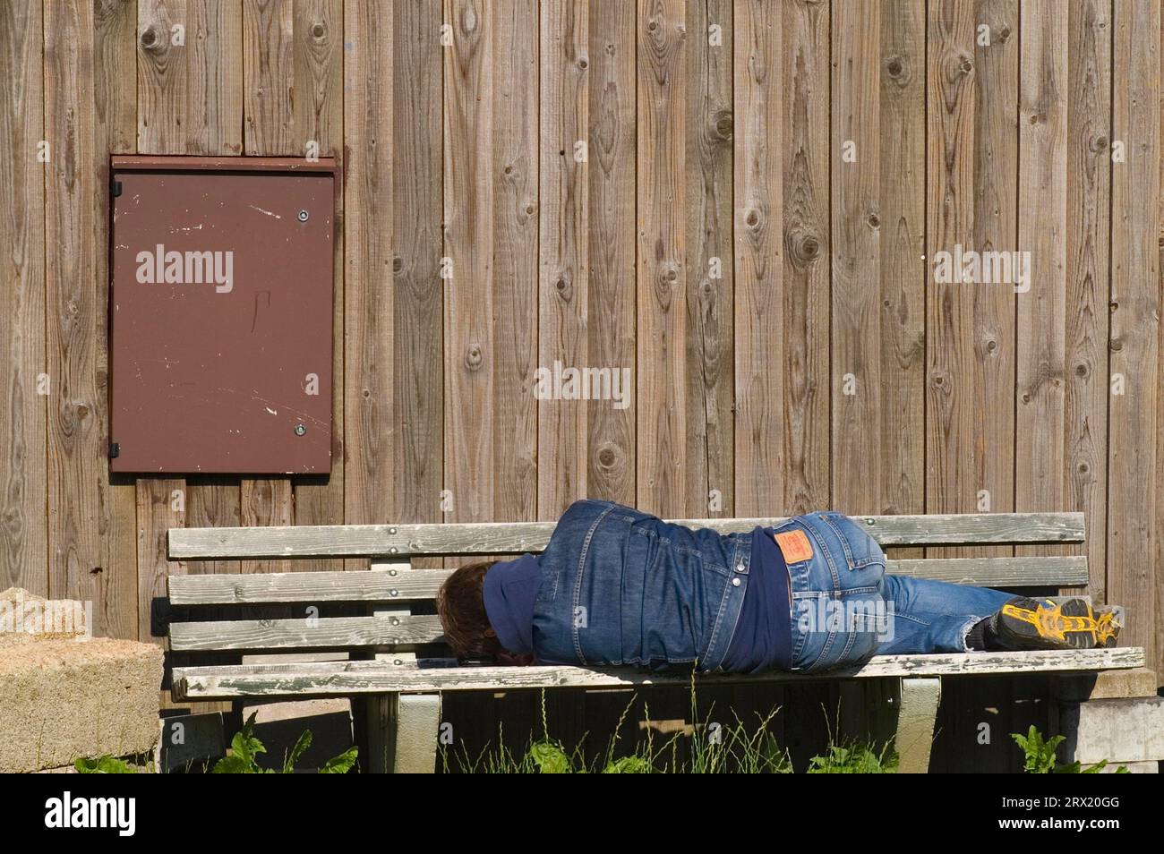A tired man lies on a bench and rests Stock Photo