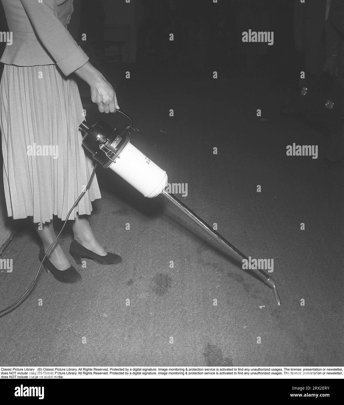 Vacuuming in the 1950s. A woman demonstrates the new vacuum cleaner from Siemens. Light and portable, the product was of the time, not unlike the appearance of today's cordless versions of vacuum cleaners. Sweden 1950. Kristoffersson ref BA61-6 Stock Photo