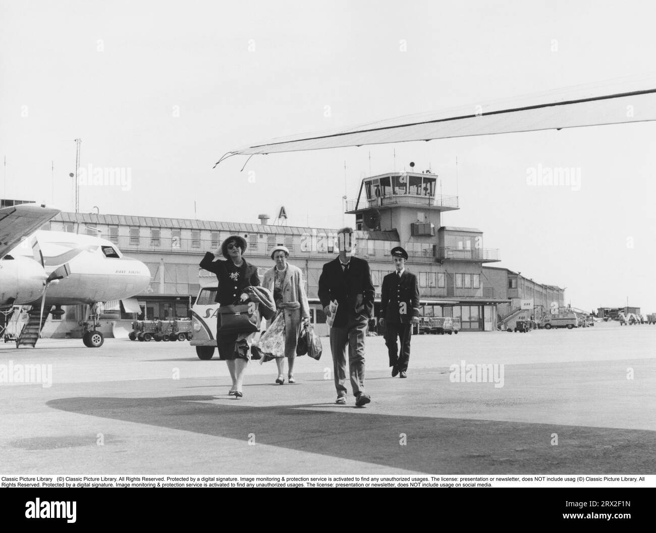 1950s vacation. A group of people are walking to the airplane from the airport terminal at Bromma airport Stockholm Sweden. 1957 Stock Photo