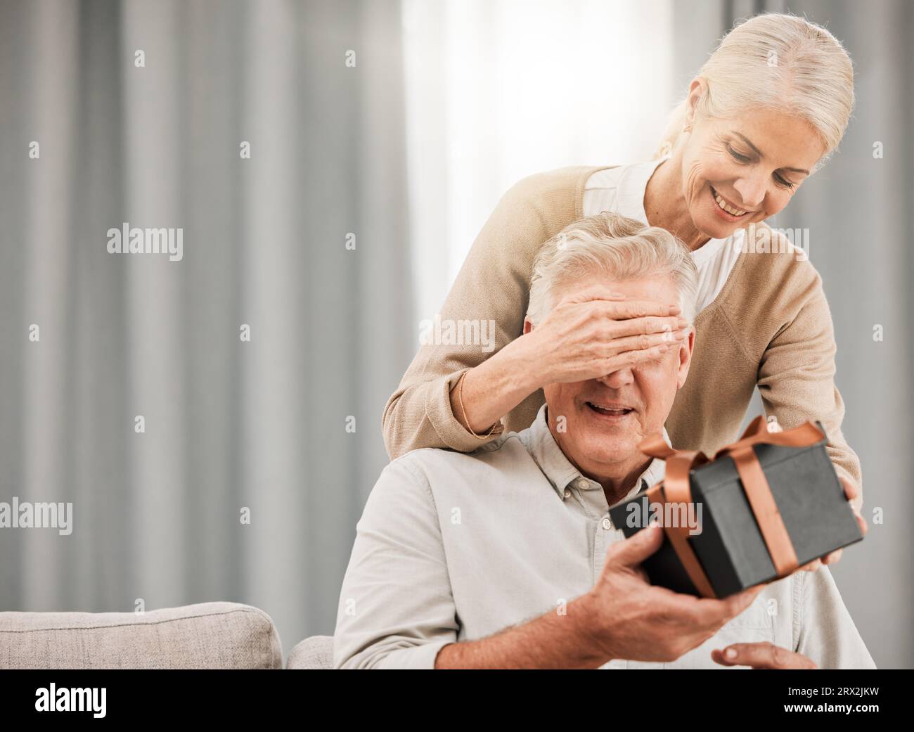 Old couple, present for birthday and surprise with celebration, man and woman at home with love and grand gesture. Gift box for special event Stock Photo