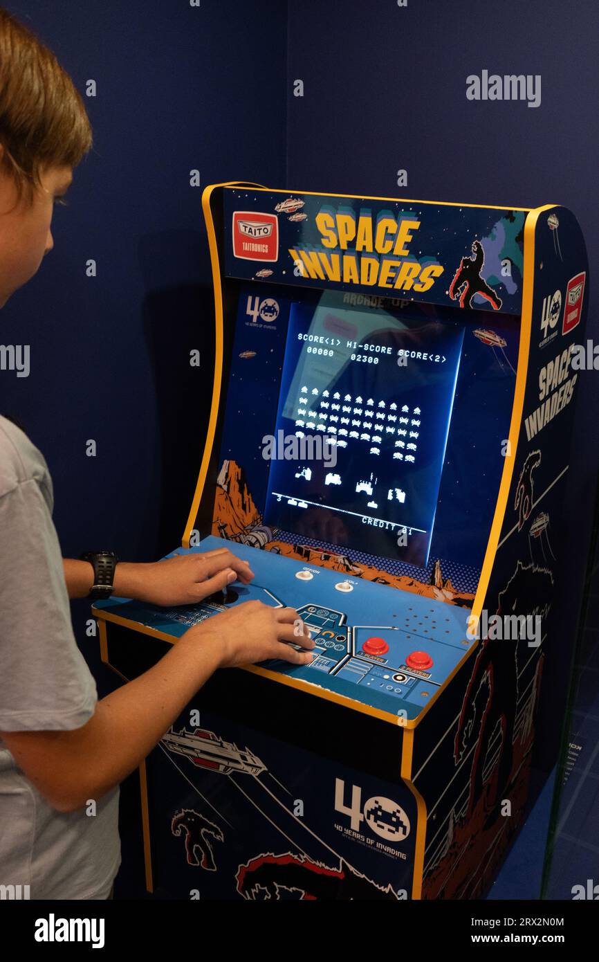 Space invaders Taito game machine. Simple Space Arcade in 8-bit retro video old game. Boy plays classic slot machine. Warsaw, Poland - July 28, 2023. Stock Photo