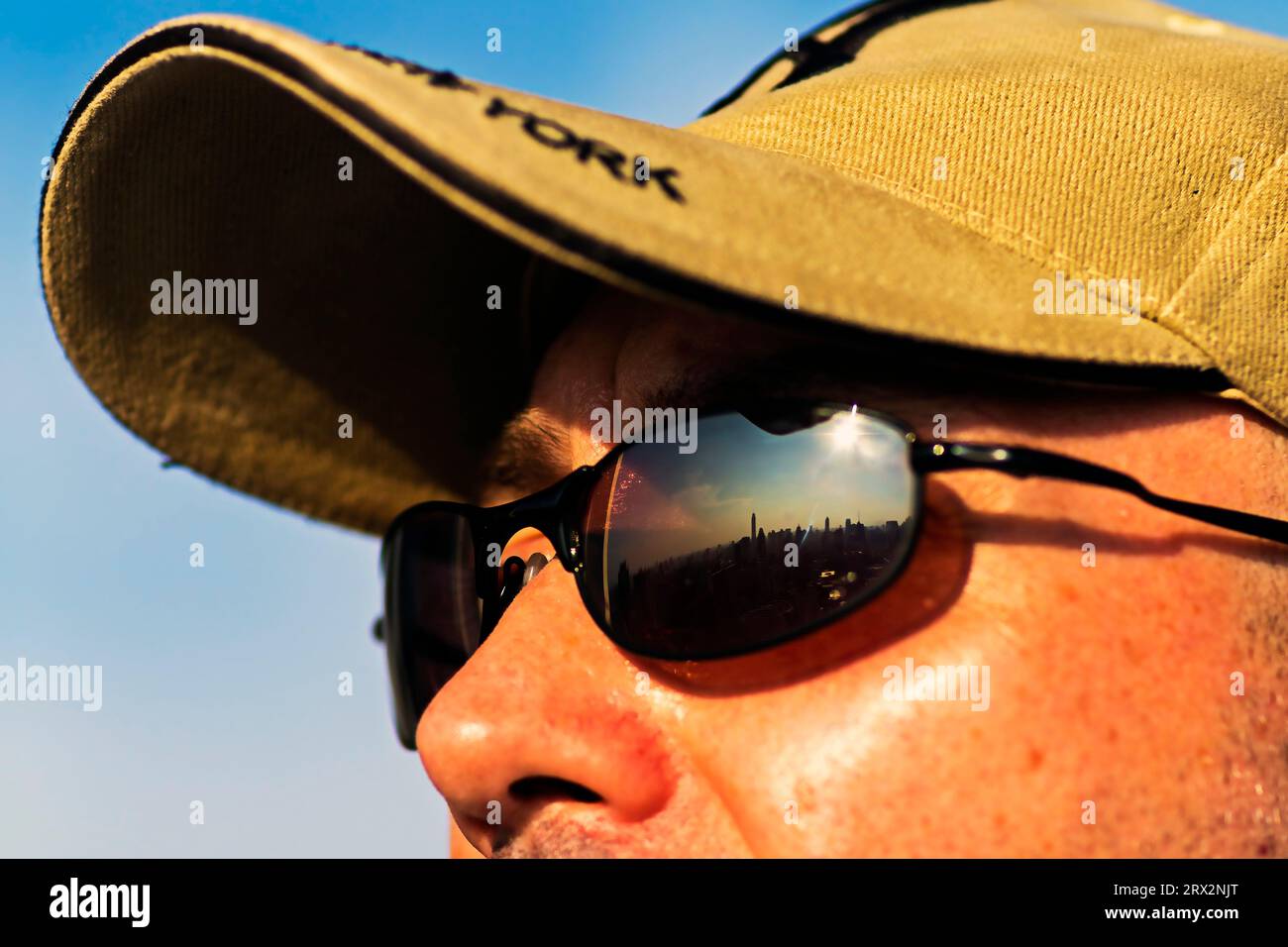 Mature man posing with baseball cap and sunglasses reflecting Bangkok skyline, Thailand Stock Photo