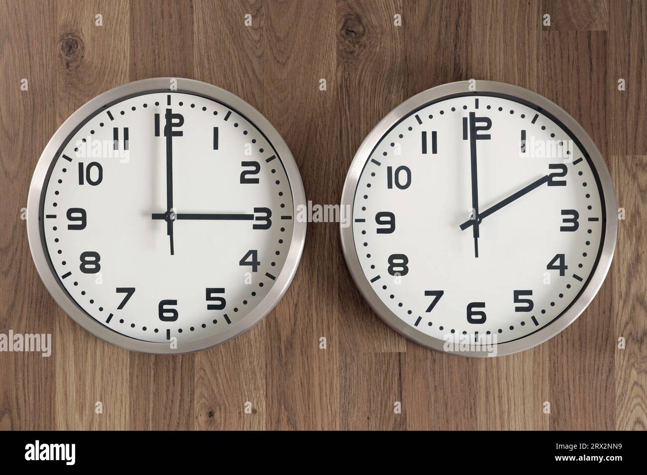Two clocks, one showing two o'clock, the other showing three o'clock.  Time change symbol. Daylight saving time. Moving the hands forward. Stock Photo