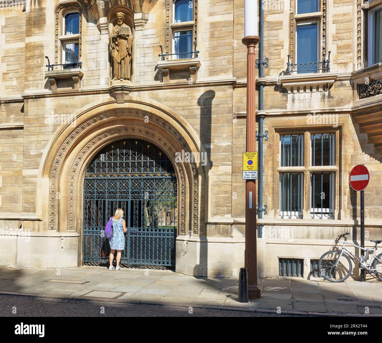 A lone woman tourist outside the prestigious college of Gonville & Caius at the university of Cambridge, England. Stock Photo