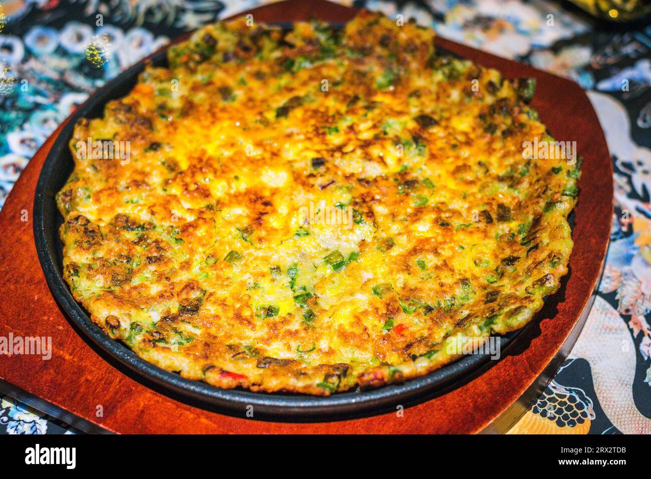 Korean pancake with seafood served on an iron plate and wood base Stock Photo