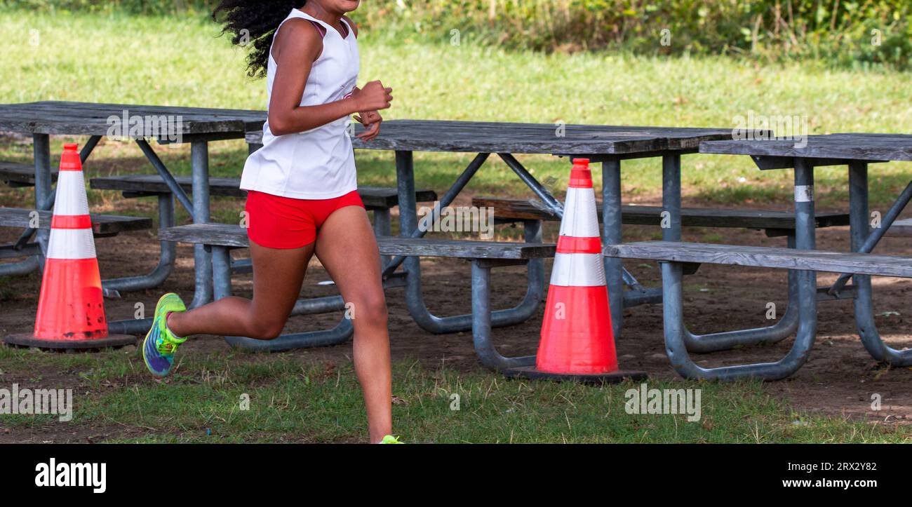 Side View Of A High School Girl Running Next To A Picnic Table During A side-view-of-a-high-school-girl-running-next-to-a-picnic-table-during-a