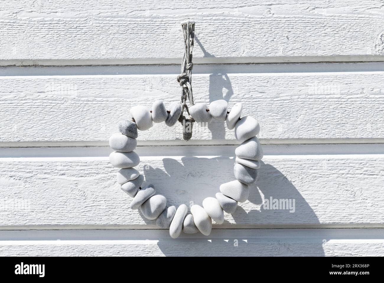 Heart-shaped string of white pebbles in front of the white wooden facade of a bathing hut on the beach of Skanör med Falsterbo, Skåne, Sweden Stock Photo