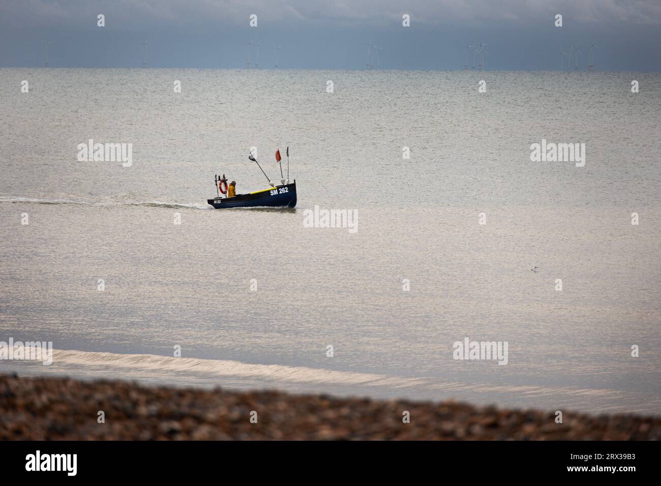 fisherman in his boat in the early morning, off the coast at Worthing, West Sussex, UK Stock Photo