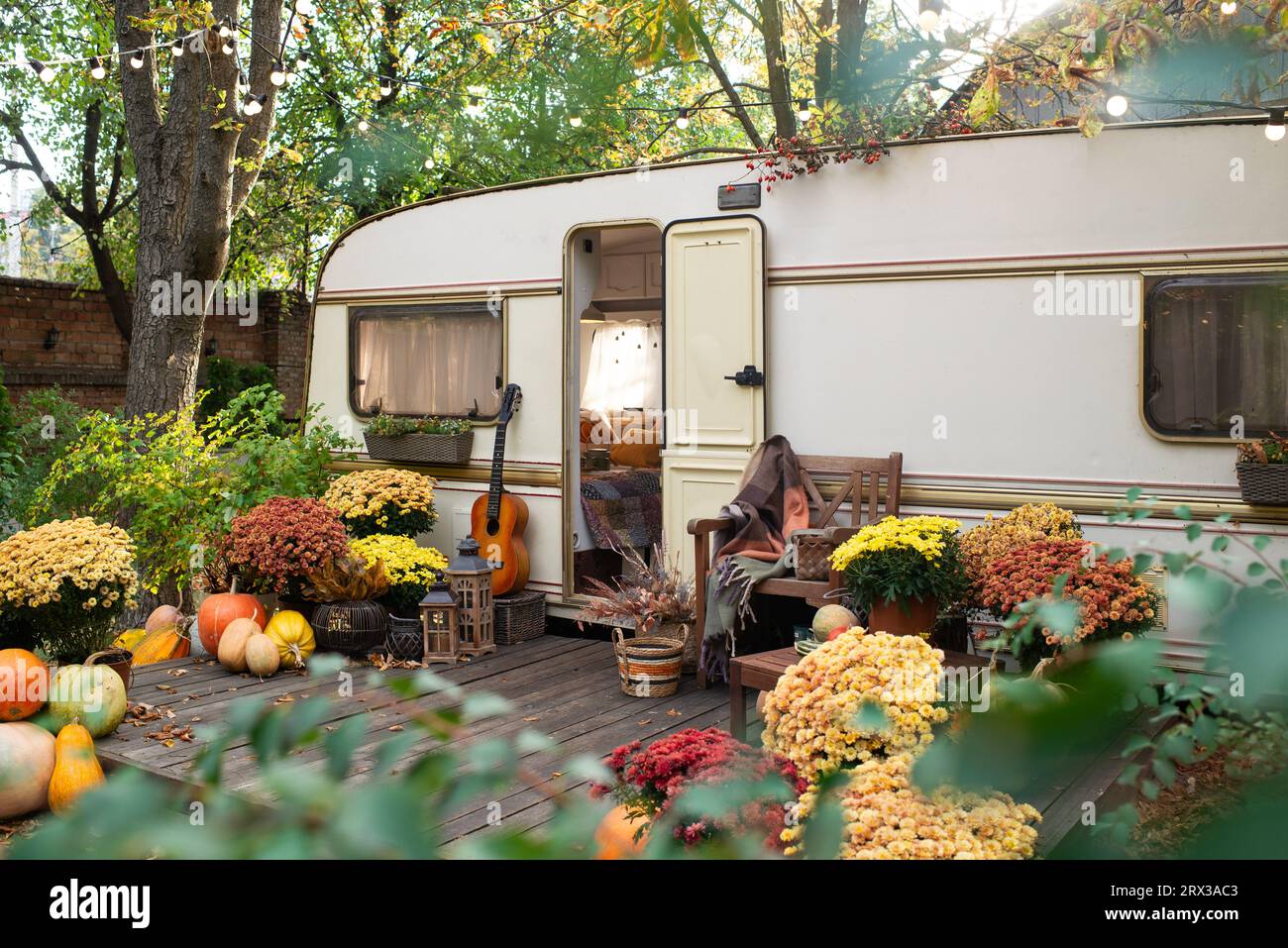 Mobile home van with terrace at sunset in autumn, mobile home, orange fallen leaves. autumn decor, pumpkins Stock Photo