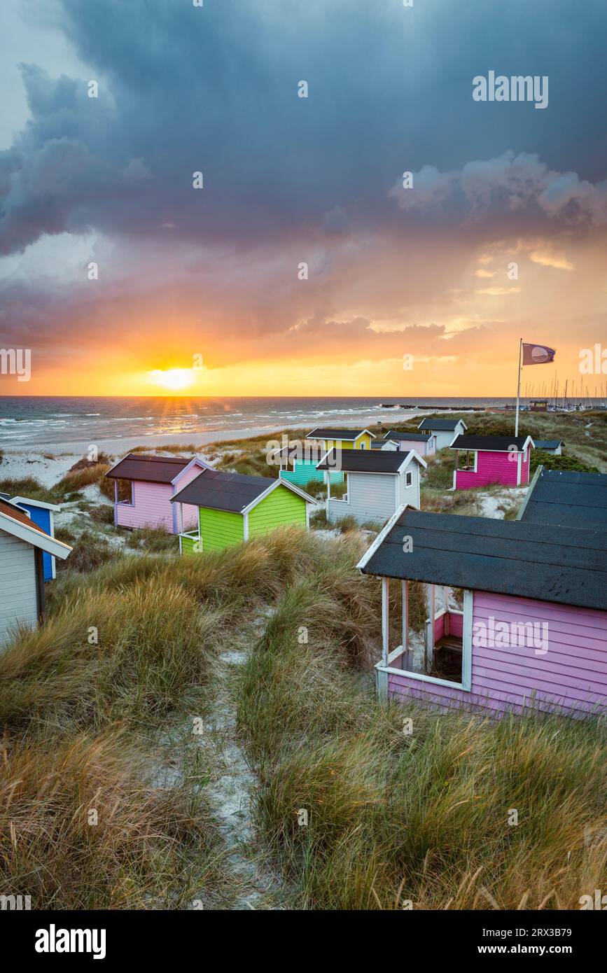 Wind and clouds at sunset over the colourful bathing huts in the sand dunes on the beach of Skanör med Falsterbo at Öresund, Skåne, Sweden Stock Photo