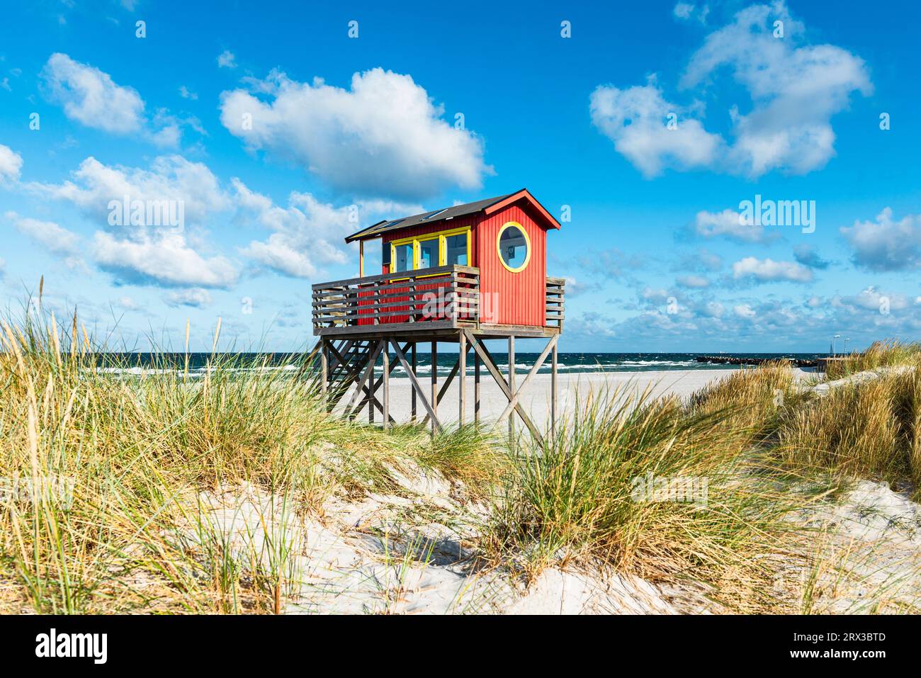 Red wooden lifeguard observation tower on stilts at the beach bar in the sand dunes on Skanör med Falsterbo beach in the morning sun, Skåne, Sweden Stock Photo