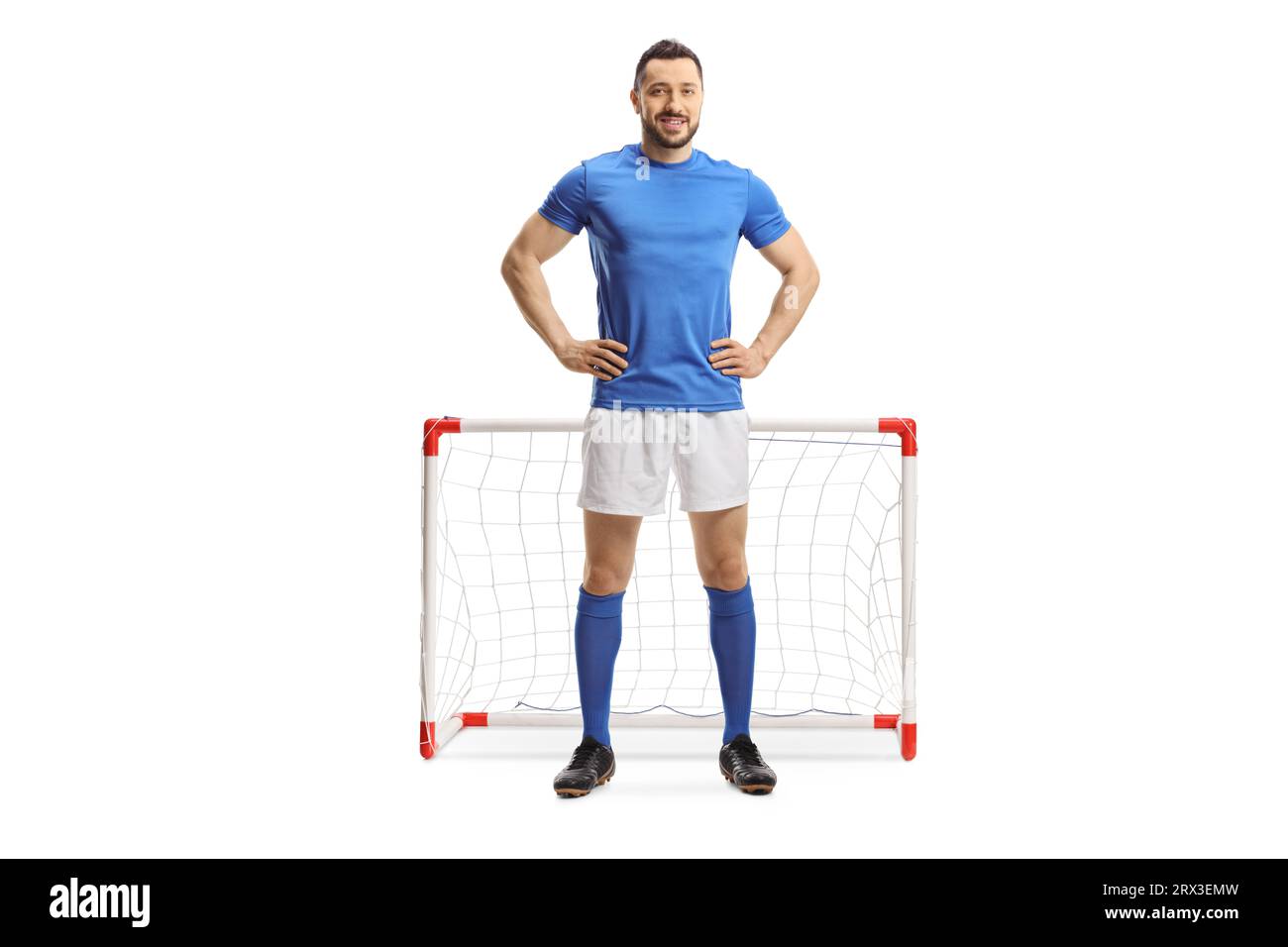 Full length portrait of a soccer player in a blue top and white shorts in front of a mini goal isolated on white background Stock Photo