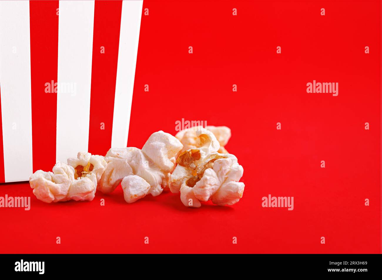 Glass with popcorn on a red background close-up Stock Photo