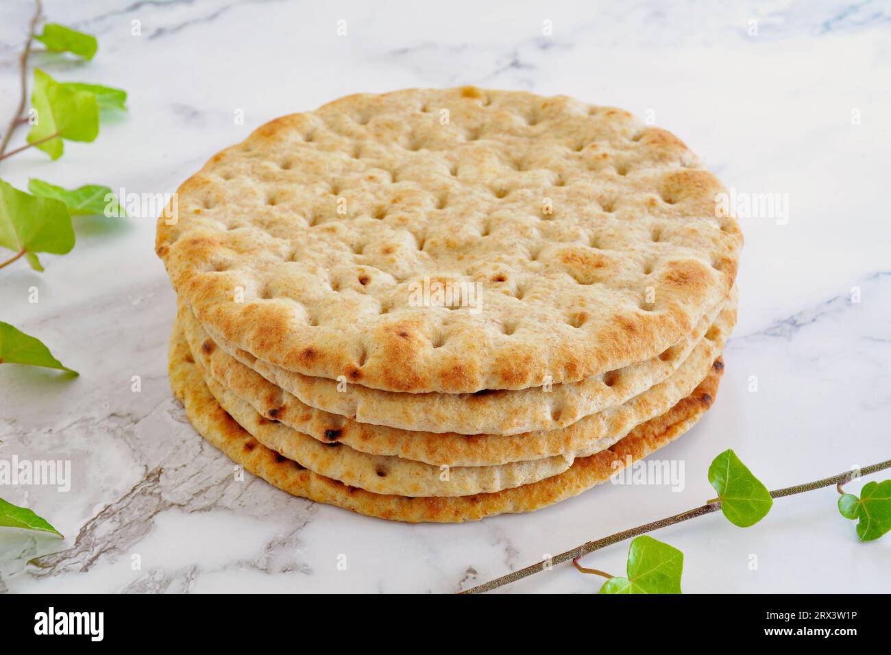Greek style whole wheat pita bread on marble background with ivy sprigs in horizontal format