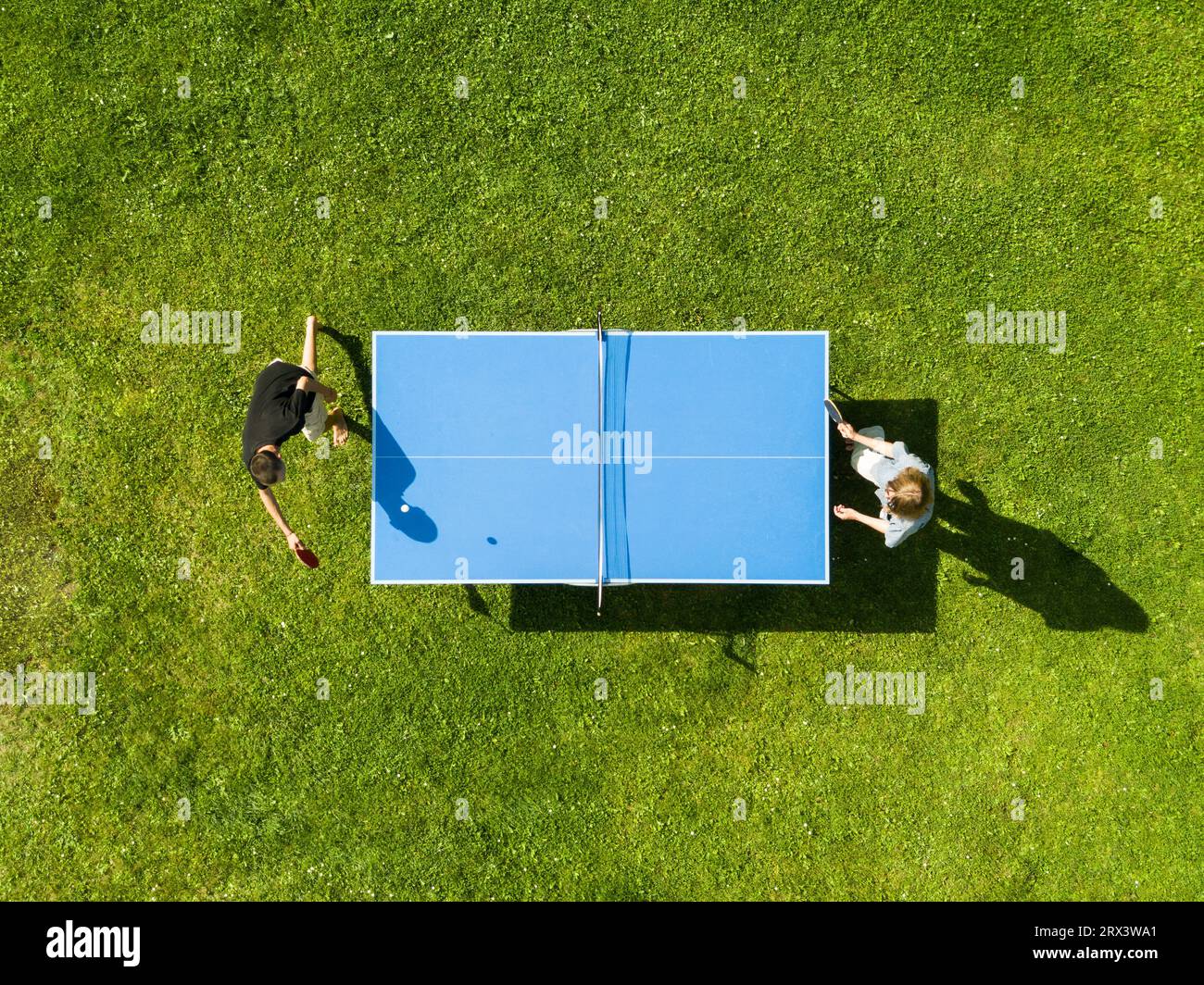 Aerial view people playing ping pong match outdoor. Top view two boys playing table tennis on a green grass lawn. Aerial view outdoor sport Stock Photo