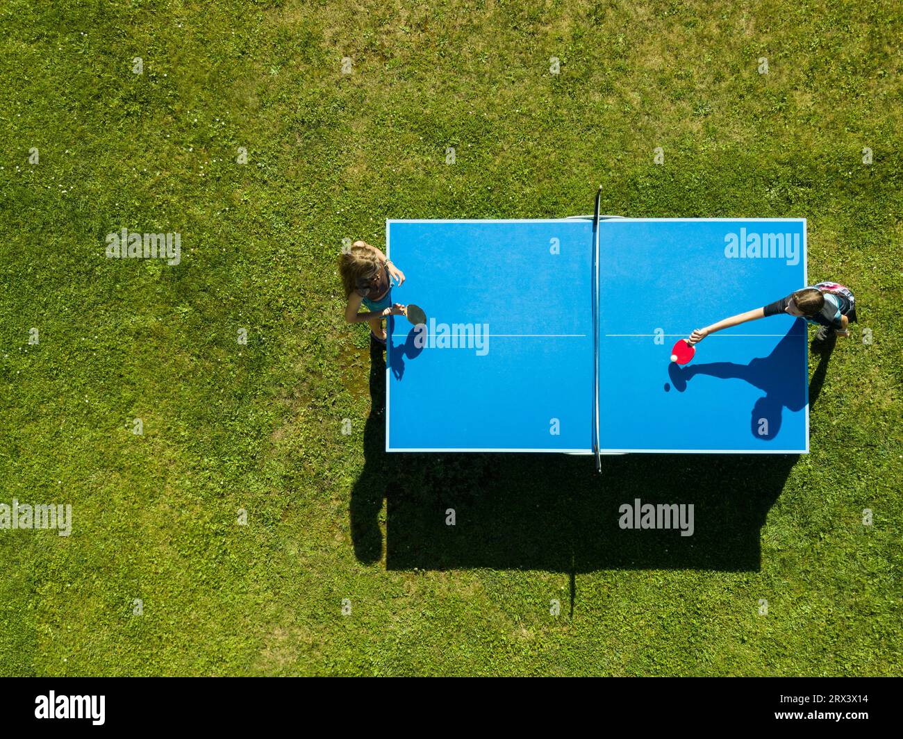 Aerial view people playing ping pong match outdoor. Top view two boys playing table tennis on a green grass lawn. Aerial view outdoor sport Stock Photo