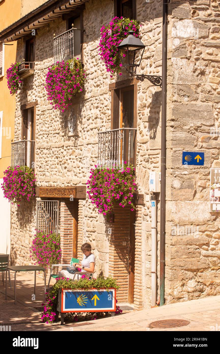 Woman pilgrim resting to read a guide book while walking the Camino de Santiago the way of St James pilgrimage route in the Spanish town of Belorado Stock Photo