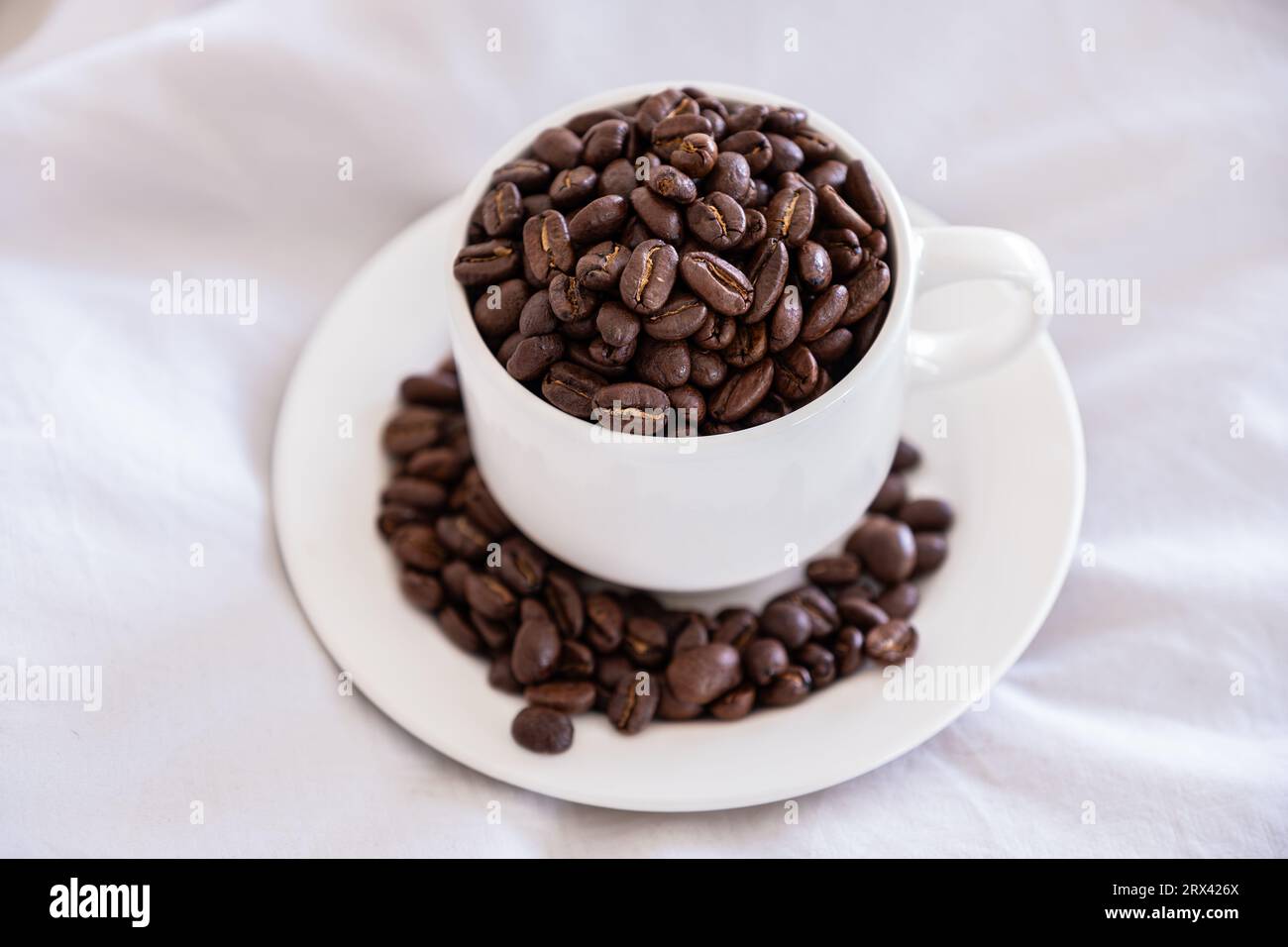 Coffee cup full of coffee beans on sleeping pillow with quilt Stock Photo