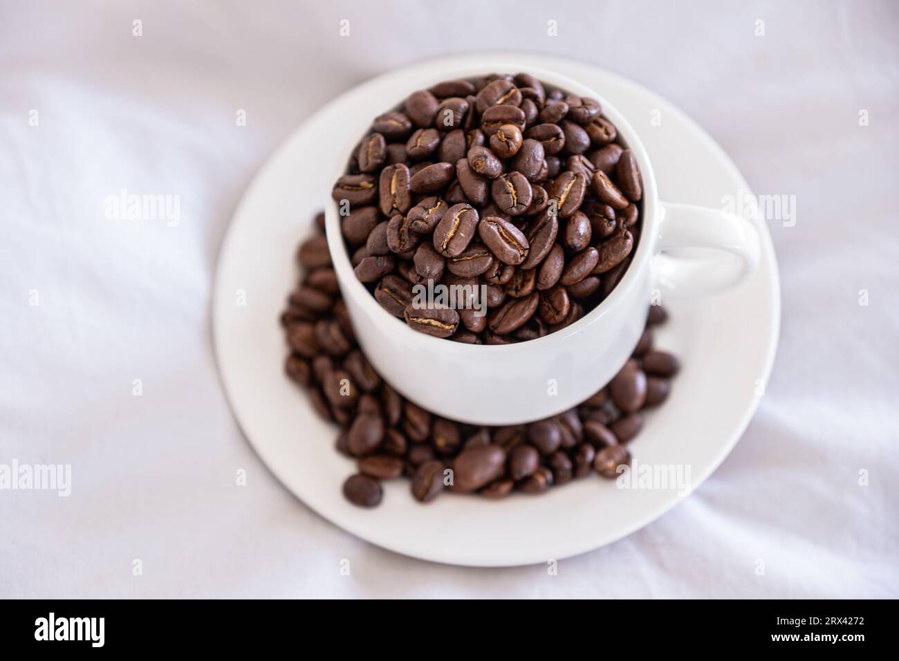 Coffee cup full of coffee beans on sleeping pillow with quilt Stock Photo