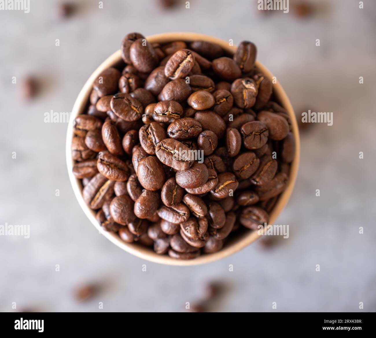 paper cup of coffee full of coffee beans  with grey background Stock Photo