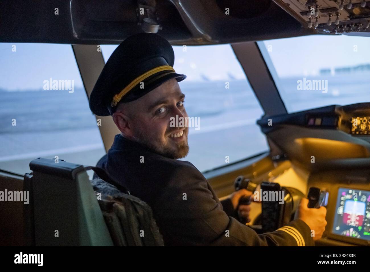 Caucasian bearded man smiling while sitting in a flight simulator. Pilot in the cockpit. Stock Photo