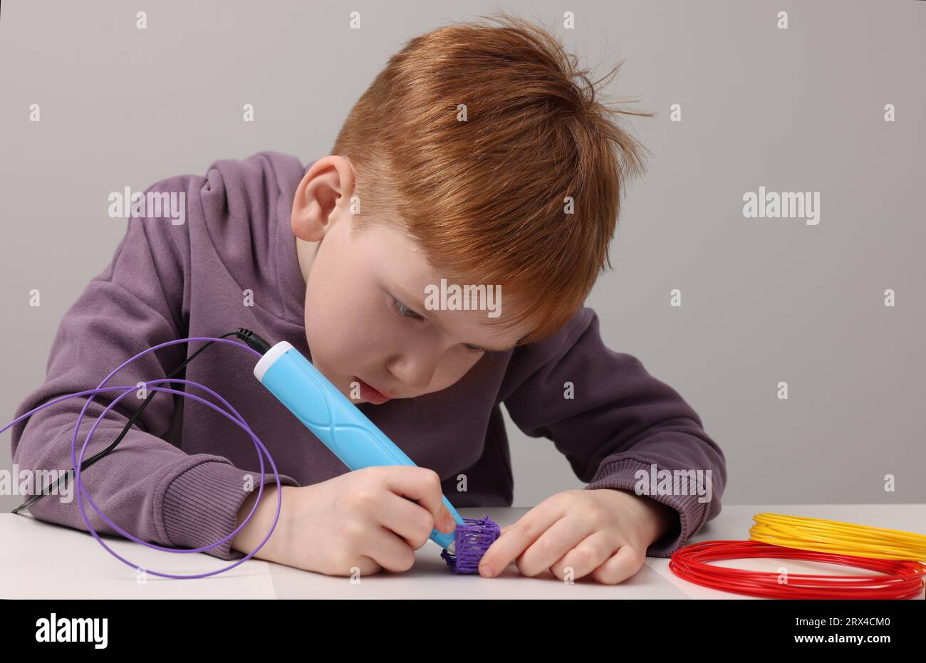 Boy drawing with stylish 3D pen at white table Stock Photo