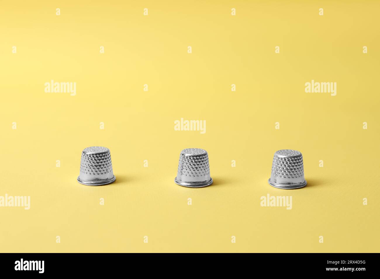 Three thimbles on yellow background. Thimblerig game Stock Photo - Alamy
