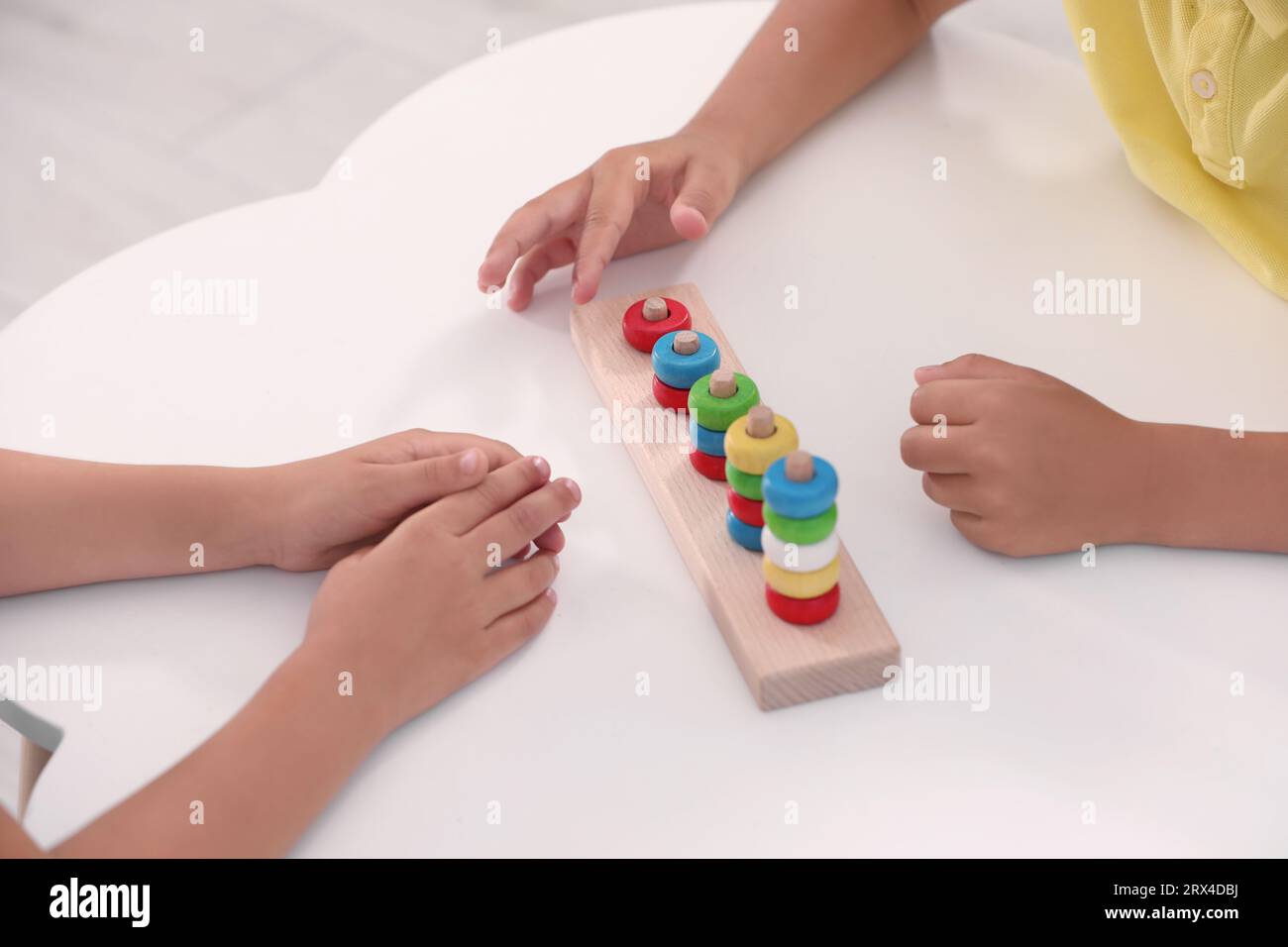 Little children playing with stacking and counting game at desk