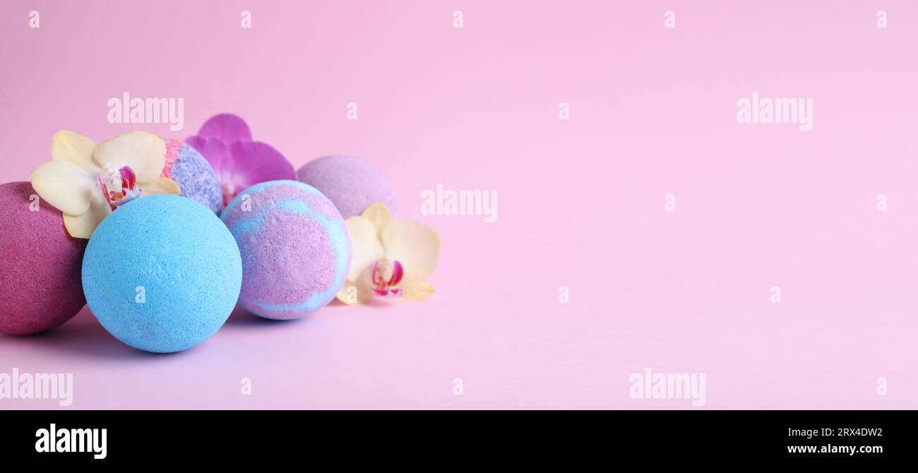 Many different bath bombs and orchid flowers on light violet background. Space for text Stock Photo