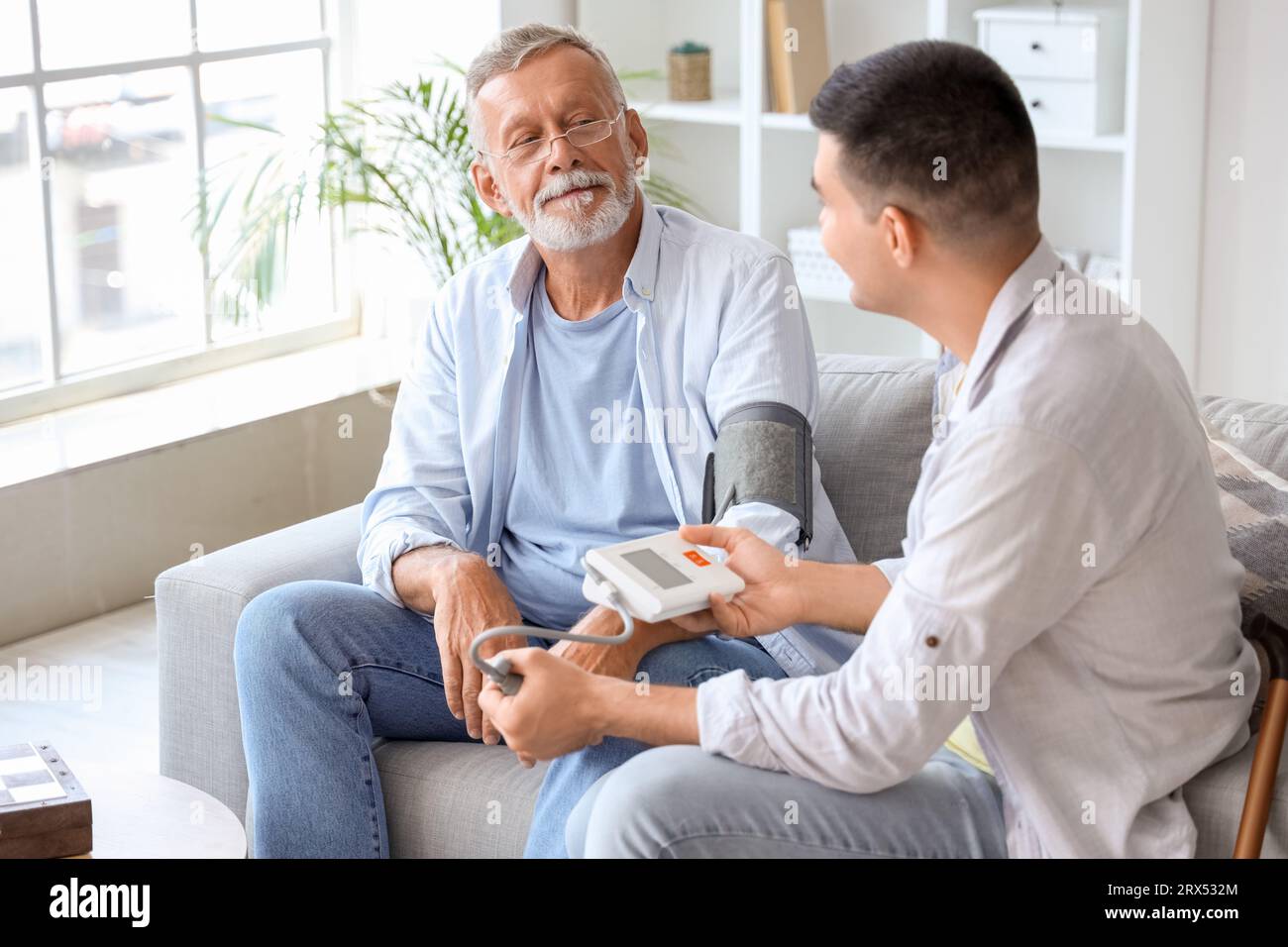 Young man measuring blood pressure of his father at home Stock Photo ...