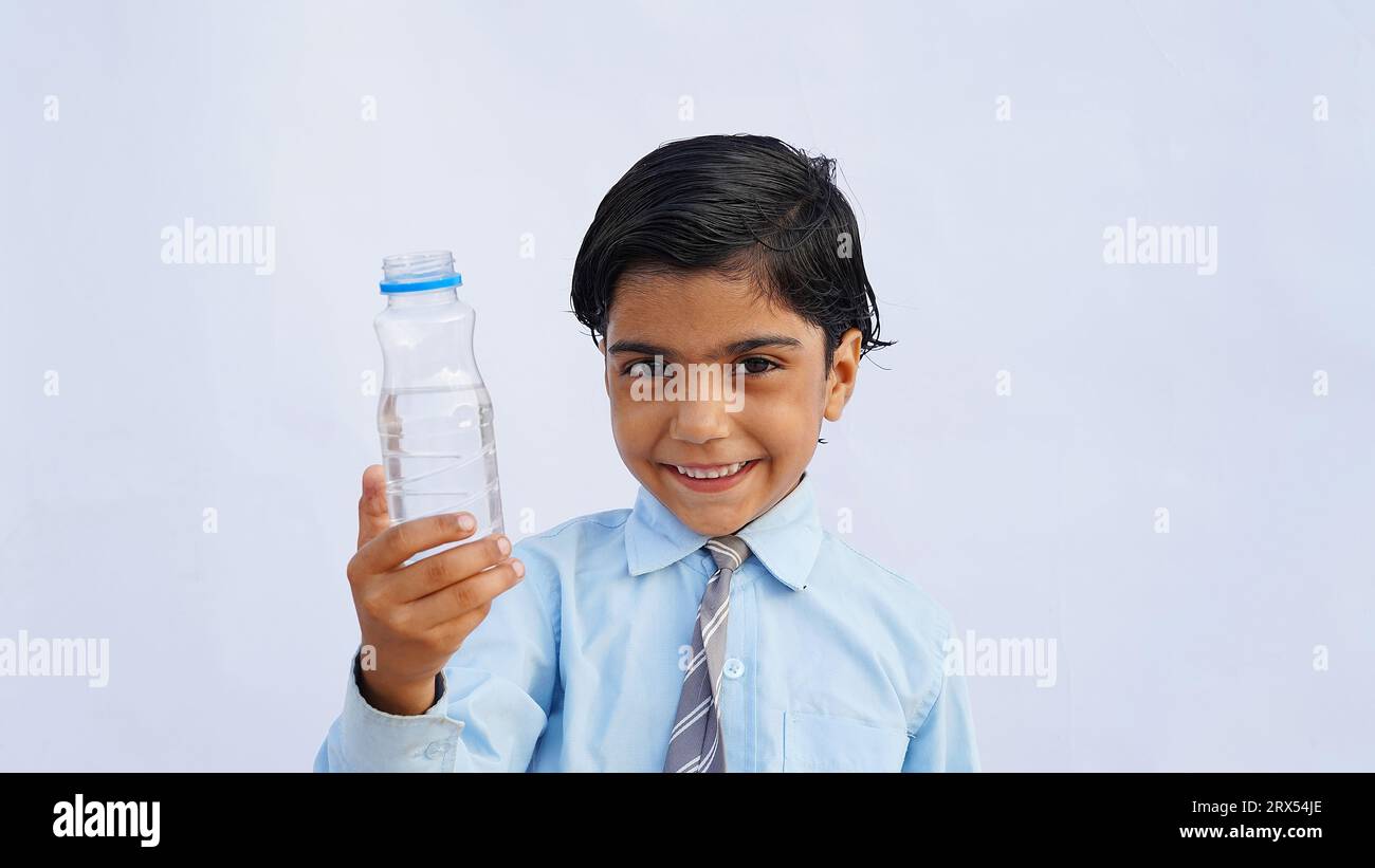 Asian school kids drink water from a bottle against the studio background. Back to school, lifestyle concept. Drinking regime. Stock Photo
