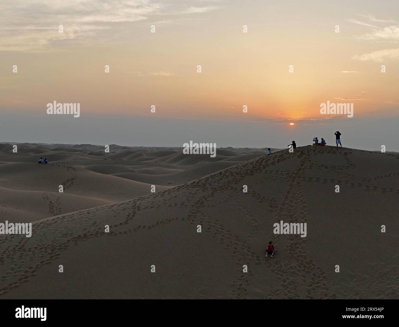 (230923) -- YINCHUAN, Sept. 23, 2023 (Xinhua) -- This aerial photo taken on Sept. 6, 2023 shows tourists enjoying the desert scene in Shapotou District of Zhongwei City, northwest China's Ningxia Hui Autonomous Region. Shapotou, literally meaning 'high sand dunes,' is a place where the Tengger Desert and the Yellow River meet. This district was faced with severe wind-sand damages, where shifting yellow sands covered farmland. Through years of dedicated efforts, local people have been combating desertification with grass pane sand fence and sand-fixing system, halting the spread of desert. (Xin Stock Photo