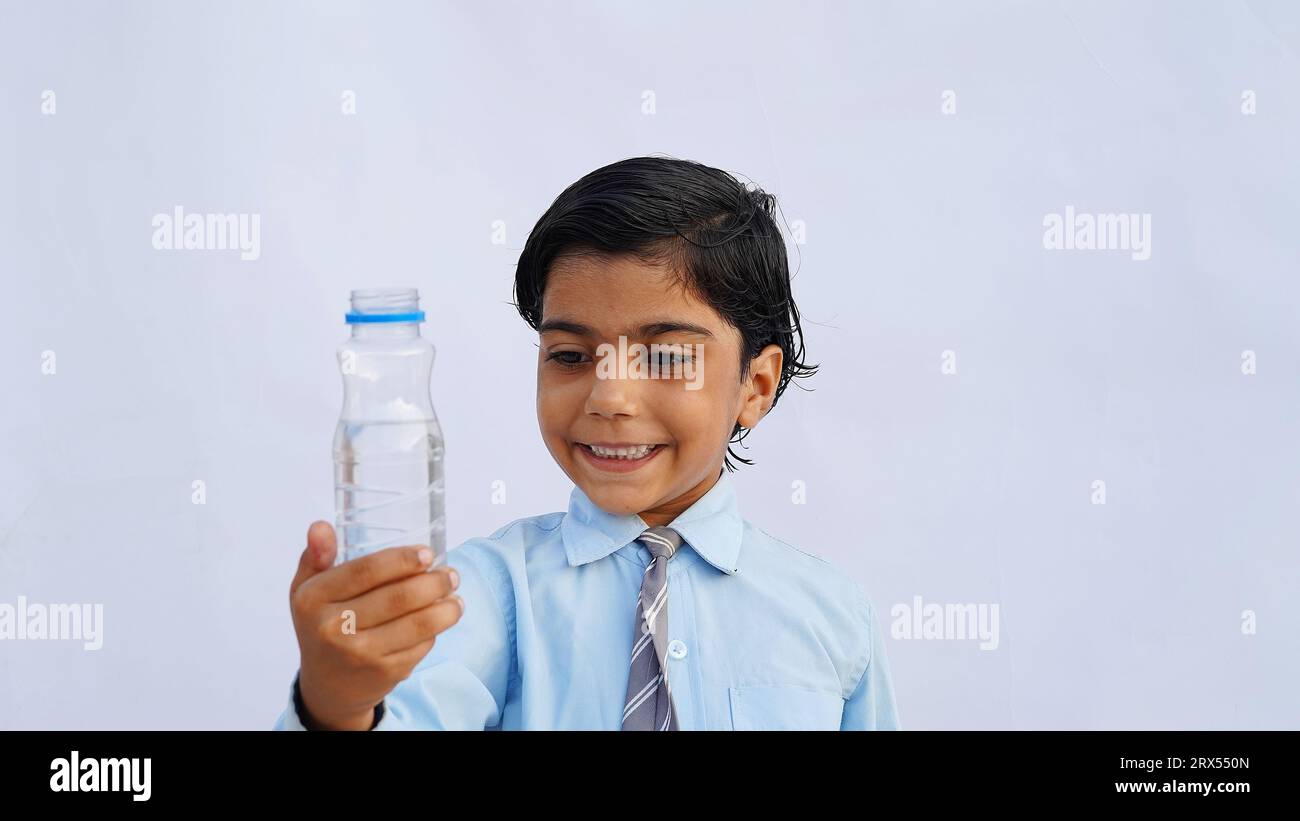 Asian school kids drink water from a bottle against the studio background. Back to school, lifestyle concept. Drinking regime. Stock Photo