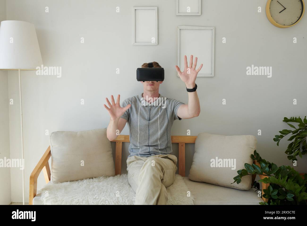Young man in virtual reality headset touching invisible objects Stock Photo