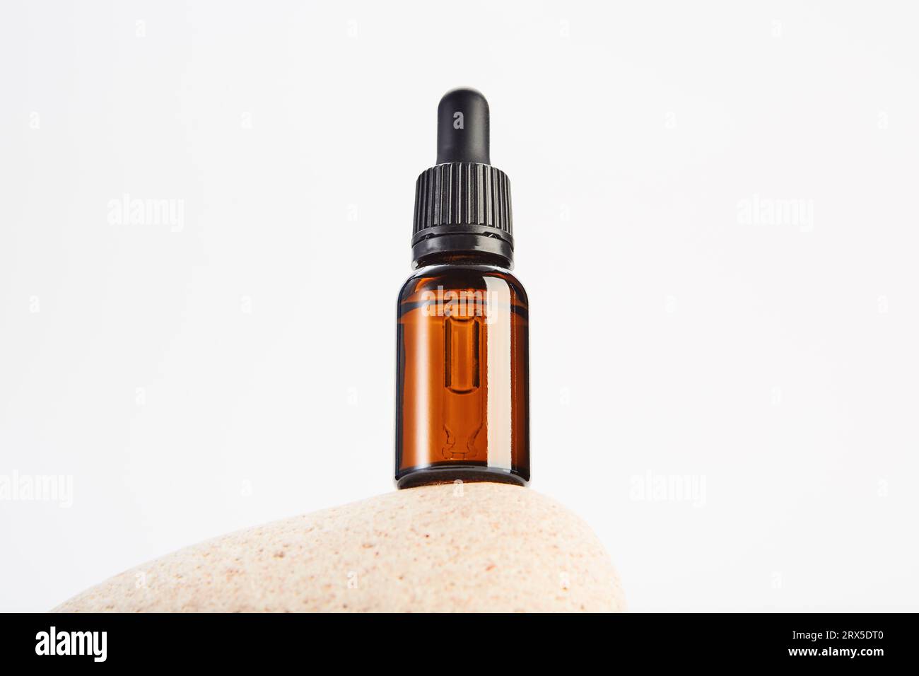 Brown dropper bottle without label is on light stone. Stock Photo
