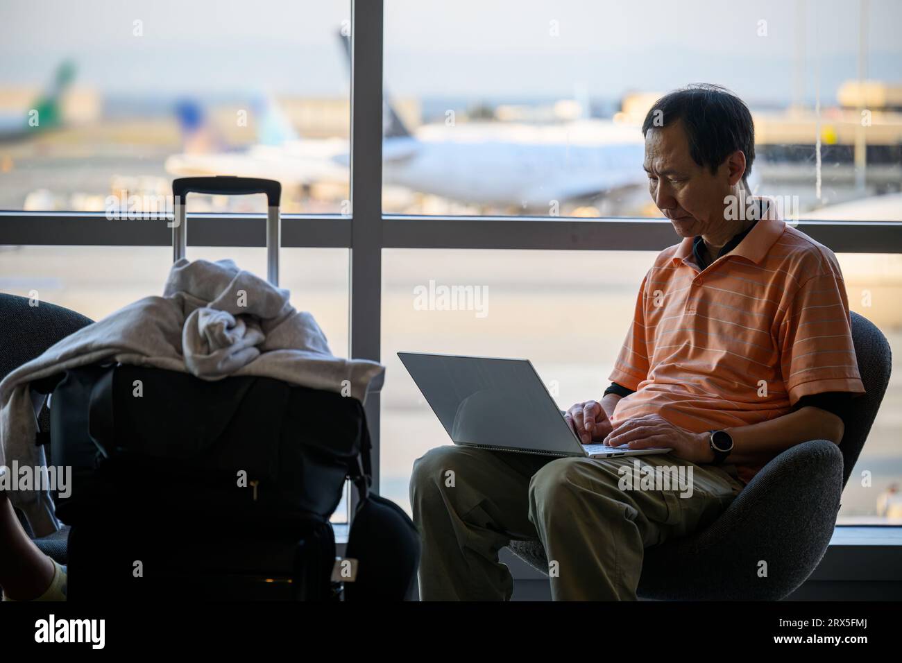 Man working on a laptop computer at the airport. Traveller remote work