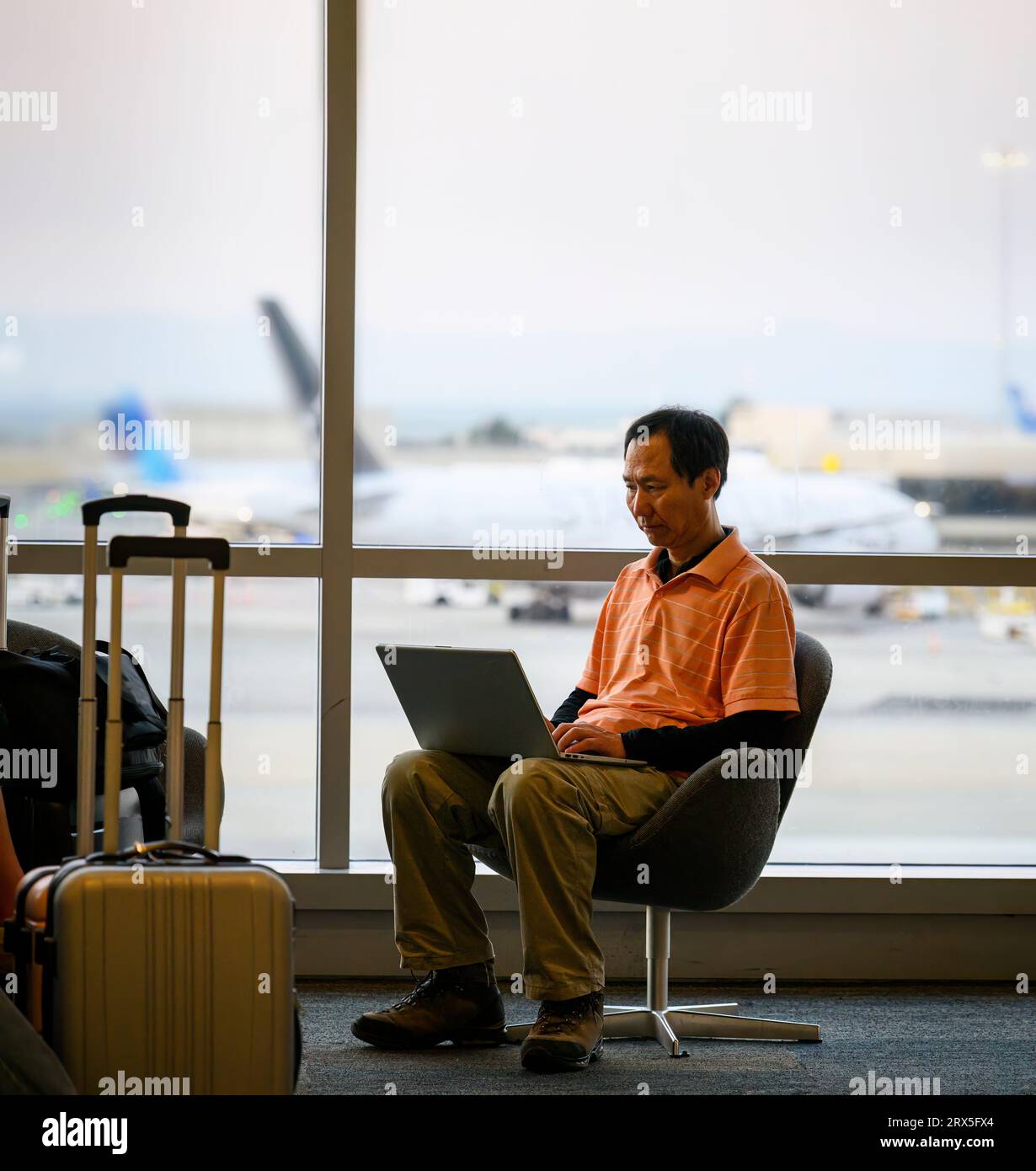 Man working on a laptop computer at an airport. Traveller remote work